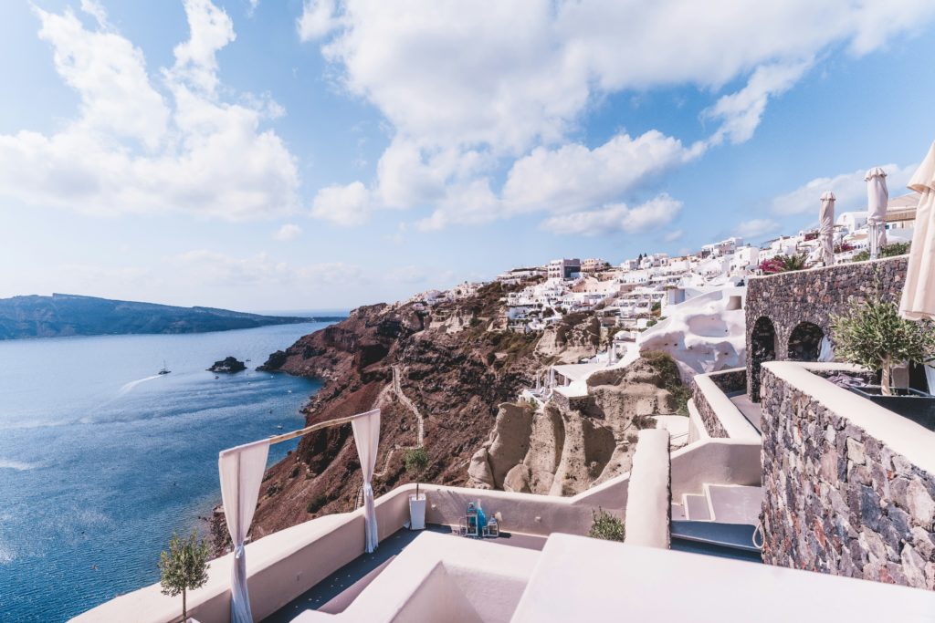Whitewashed terraces and stone walls above the sea, with a winding path across the cliffside.