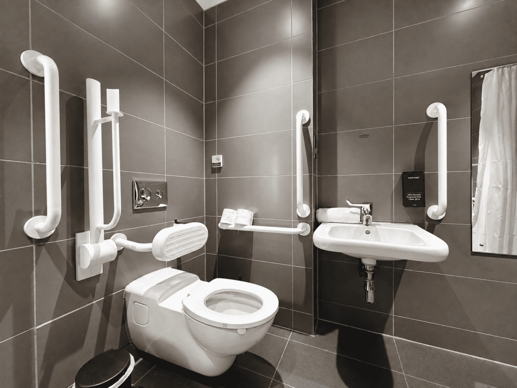 Accessible bathroom at Staycity Manchester Piccadilly with toilet support rails, lowered sink and mirror.
