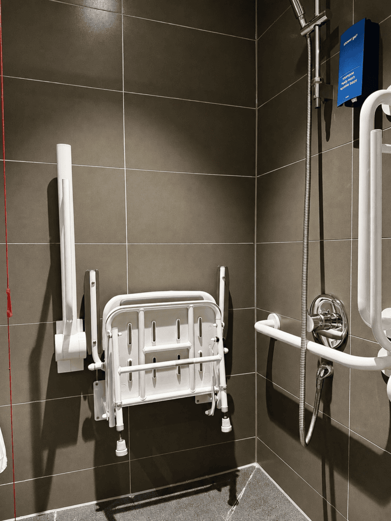 Accessible bathroom at Staycity Manchester Piccadilly with toilet support rails, lowered sink and mirror.