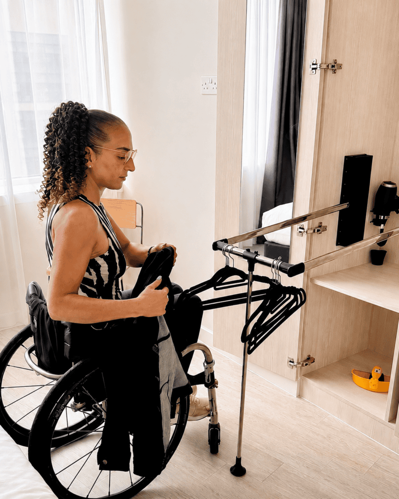 Wheelchair user hanging clothes independently using the pull-down wardrobe rail at Staycity Manchester Piccadilly.
