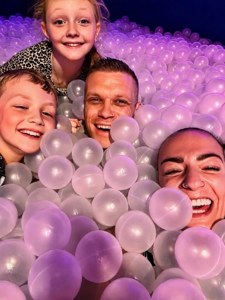 Family of four enjoying the purple ball pit at Bubble Planet Manchester during an accessible family city break.