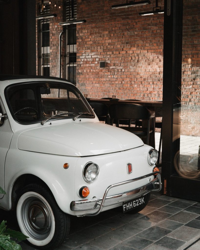 A white Fiat 500 beneath the brick arches at Amelia Hall.